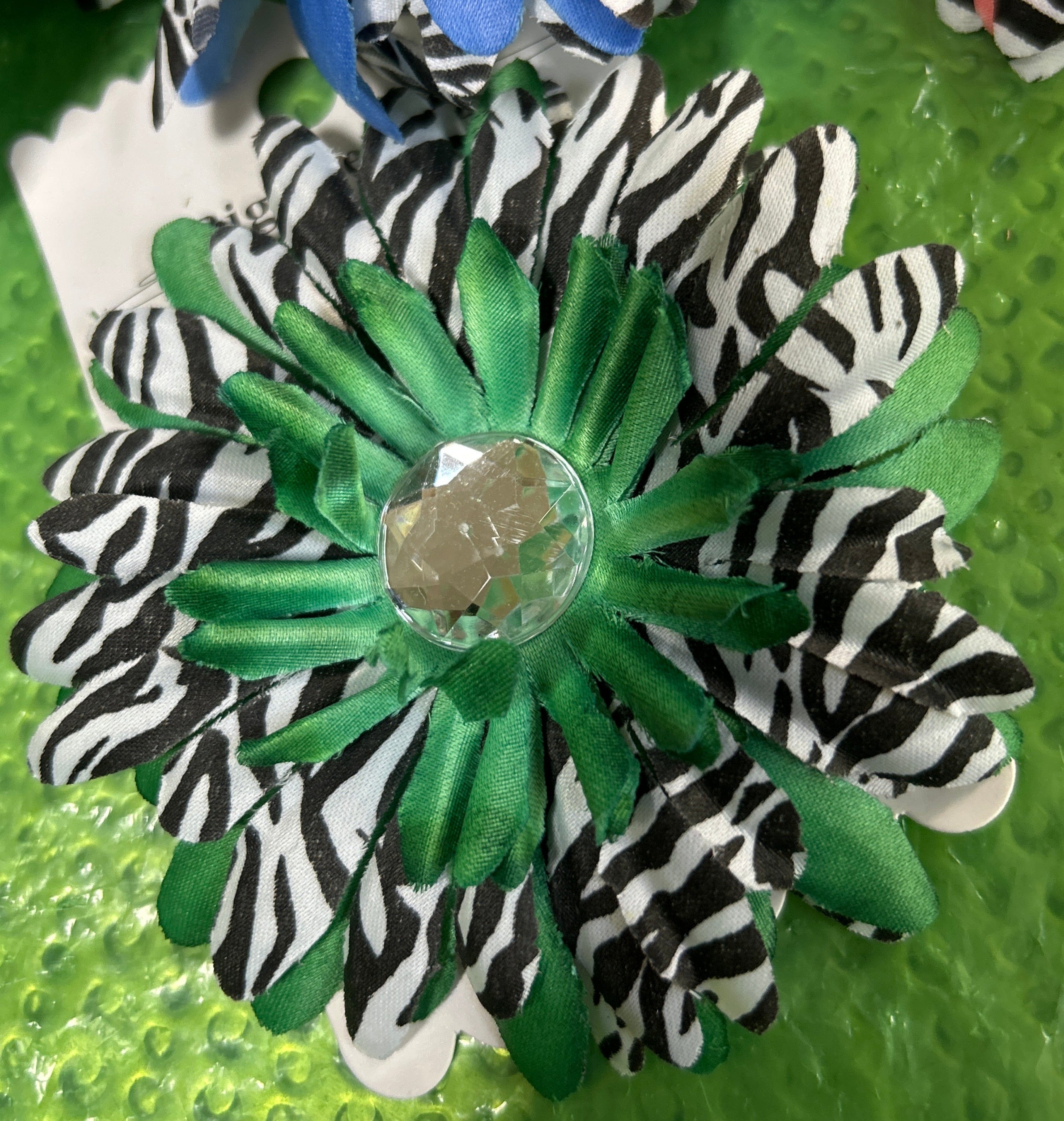 Zebra-striped flower-shaped hair clips on a green textured background