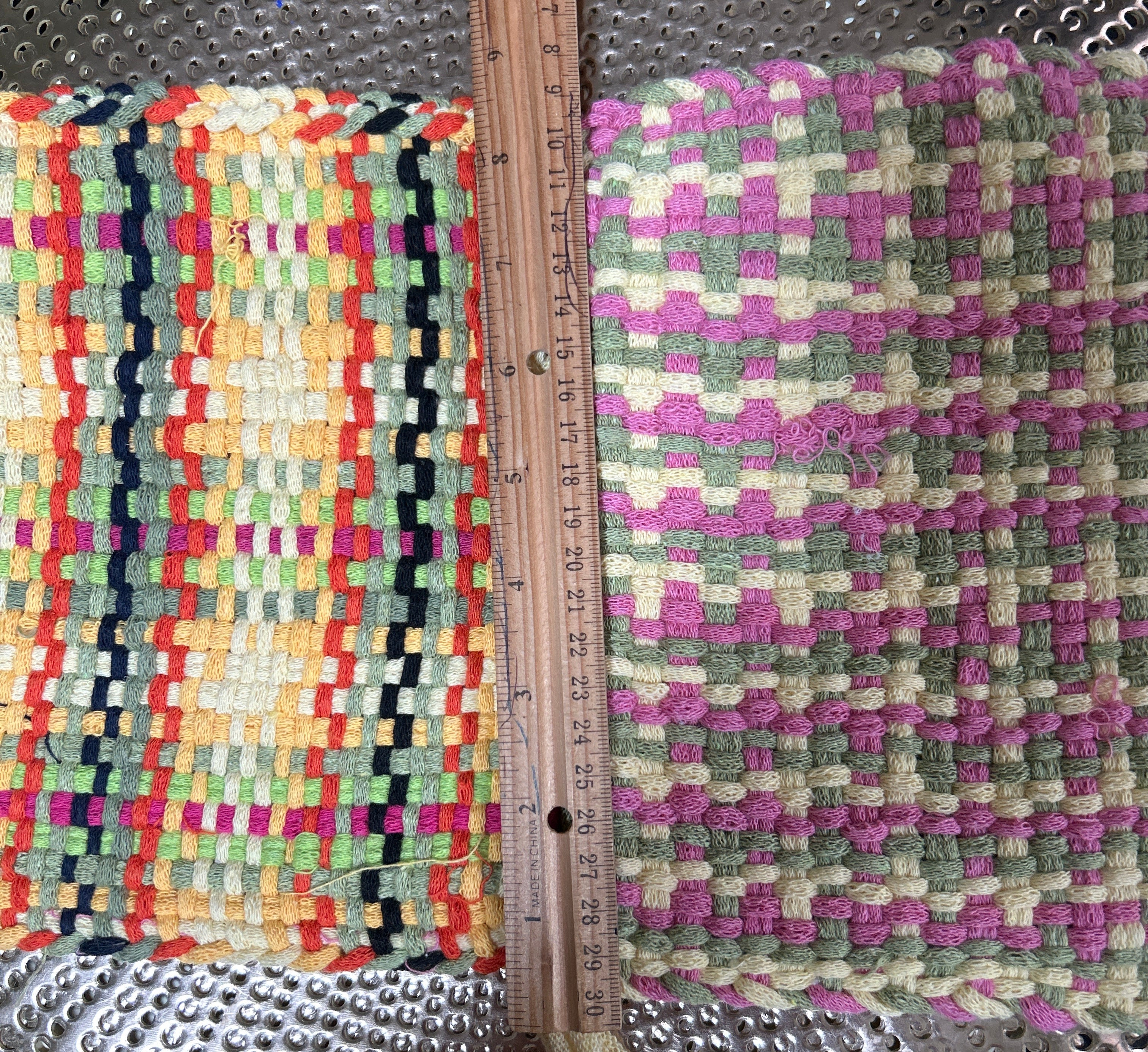 Two woven mats with different patterns and colors on a metallic surface.