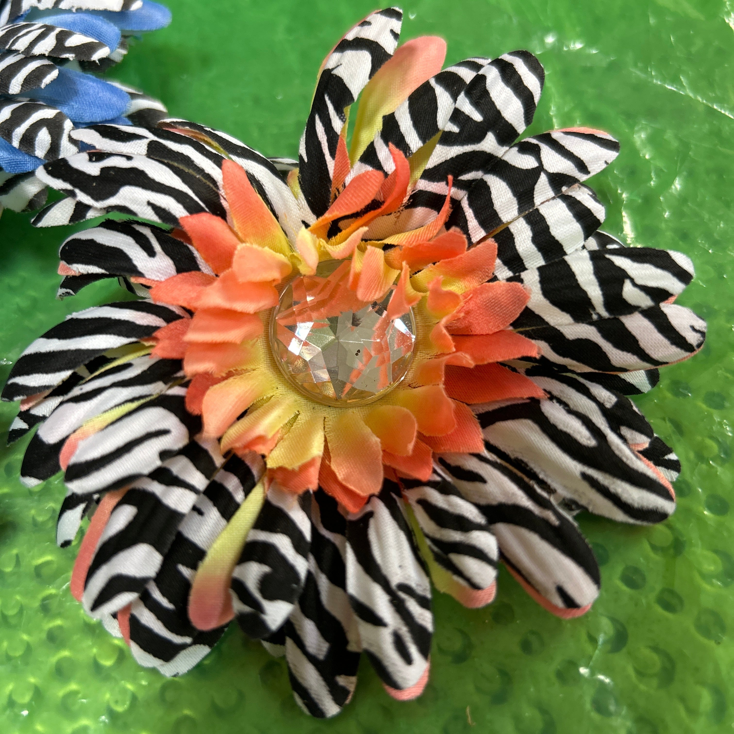 Hair clip with zebra pattern and orange flower on a green background